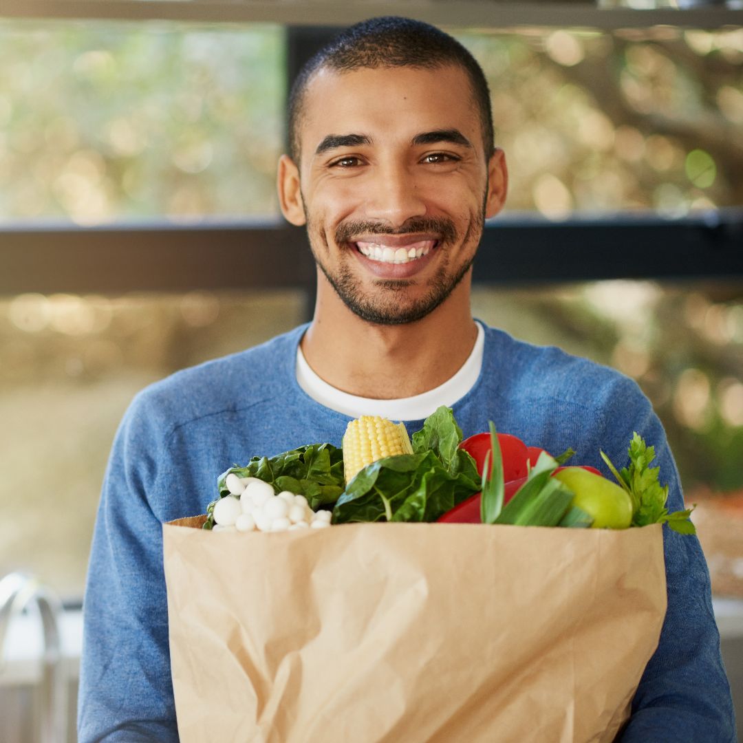 Smiling man with nice teeth holding grocery bag received periodontal treatment in Austin, TX