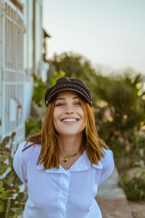 199281941 768x768 1 Smiling woman with red hair and hat smiles outside with perfect teeth form cosmetic dental care in Austin, TX